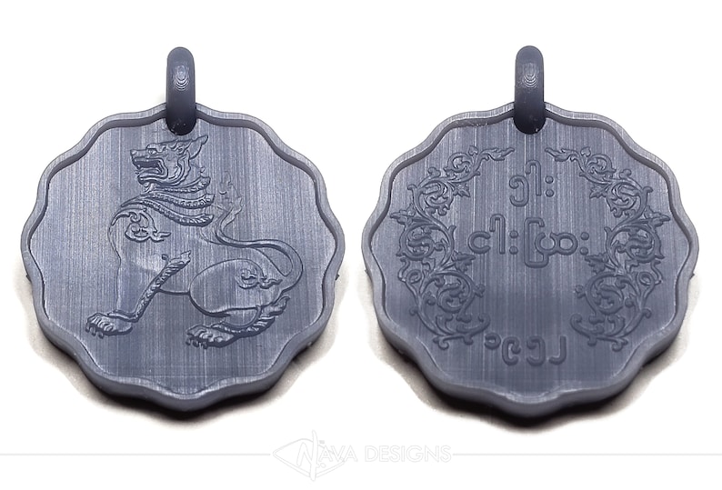 May include: A dark gray, scalloped-edge circular pendant featuring a relief of a mythical lion creature on one side and intricate floral scrollwork surrounding Burmese script text on the reverse, both topped with a small integrated loop.