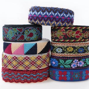 May include: A collection of decorative ribbons in a variety of colours and patterns. The ribbons display floral, geometric, and abstract designs. The colours include red, blue, green, yellow, and black. These ribbons are suitable for crafts, sewing, and embellishments.