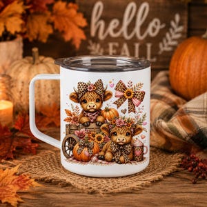 May include: A white mug with a lid featuring a graphic of two brown highland calves, pumpkins, sunflowers, and leopard print bows. The design includes autumn leaves and small hearts, creating a seasonal theme on the smooth ceramic surface.
