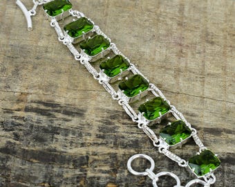 May include: A silver bracelet with a chain link design and eight emerald green rectangular gemstones.