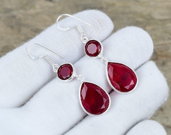 Peut inclure: Une paire de boucles d'oreilles pendantes en argent avec des gouttes de pierres précieuses rouges. Les boucles d'oreilles présentent une petite pierre précieuse ronde en haut et une plus grande pierre précieuse en forme de larme en dessous.