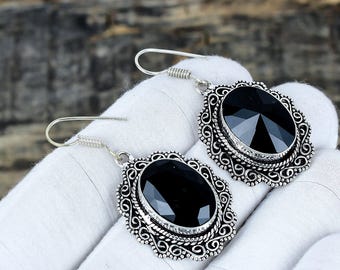 Puede incluir: Un par de pendientes colgantes plateados. Cada pendiente presenta una gran piedra preciosa negra facetada engastada en un marco ornamentado de estilo filigrana. Los pendientes tienen un cierre de gancho.