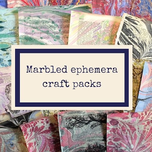 May include: A collection of marbled ephemera craft packs. The image features various papers with colorful, swirling patterns in shades of blue, pink, green, and brown. The text "Marbled ephemera craft packs" is displayed in a white rectangle with a navy blue border.