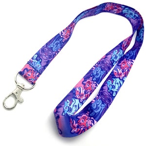 May include: A purple lanyard with a repeating pattern of pink and blue tigers. The lanyard has a silver swivel clip.