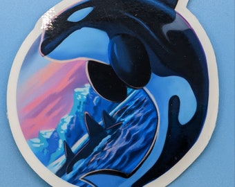 Könnte beinhalten: Ein Aufkleber mit einem blauen und schwarzen Orca-Wal, der aus dem Wasser springt. Der Hintergrund ist ein farbenfroher Sonnenuntergang mit Bergen in der Ferne.