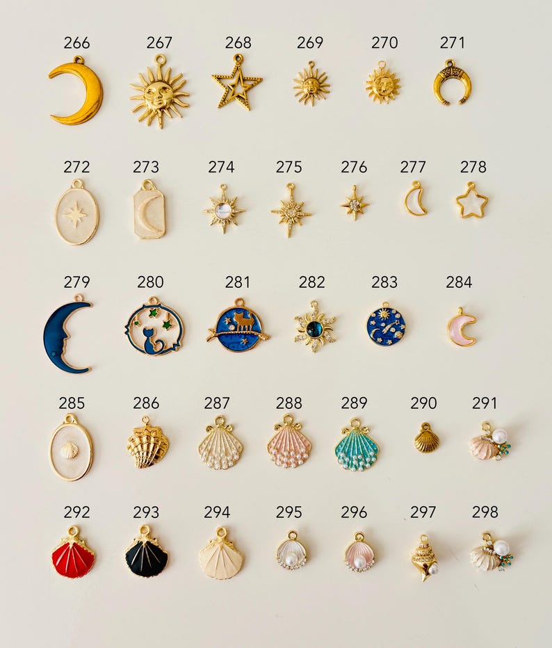 May include: A collection of small, decorative charms in various celestial and nautical designs. The charms include moons, suns, stars, seashells, and other shapes, in gold, silver, and colorful enamel finishes. These charms are ideal for jewelry making.