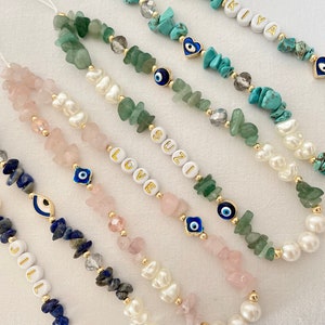 以下が含まれることがあります： ターコイズ、グリーン、ピンク、ブルーなど、さまざまなビーズが付いた5種類の携帯電話チャーム。各チャームには、金の邪眼チャームと、