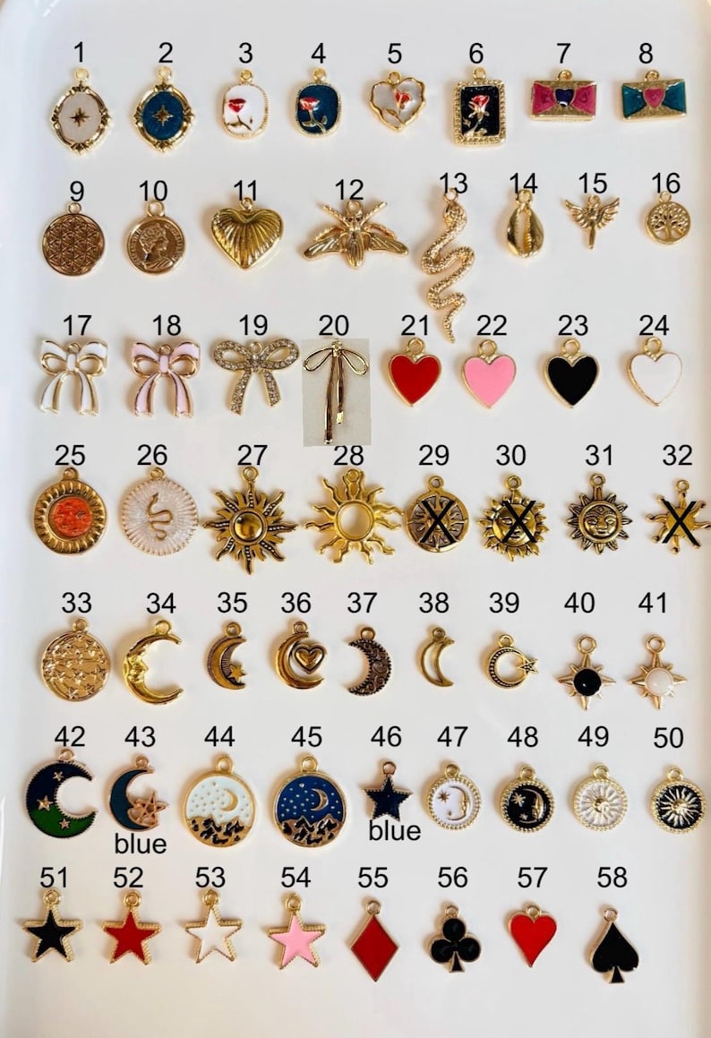 May include: A collection of 58 gold-toned and enamel charms with various designs, including hearts, moons, stars, bows, and suns. Some charms have colorful enamel details in red, blue, pink, and black. The charms are arranged in rows.