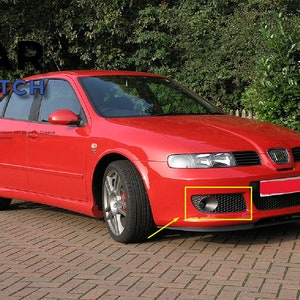 Może przedstawiać: Czerwony Seat Leon z czarnym zderzakiem przednim i czarną kratką. Samochód ma czarne tablice rejestracyjne i czarny przedni spoiler. Samochód jest zaparkowany na brukowanej podjeździe.