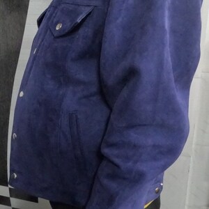 May include: A blue suede jacket with a button-up front and a single chest pocket.