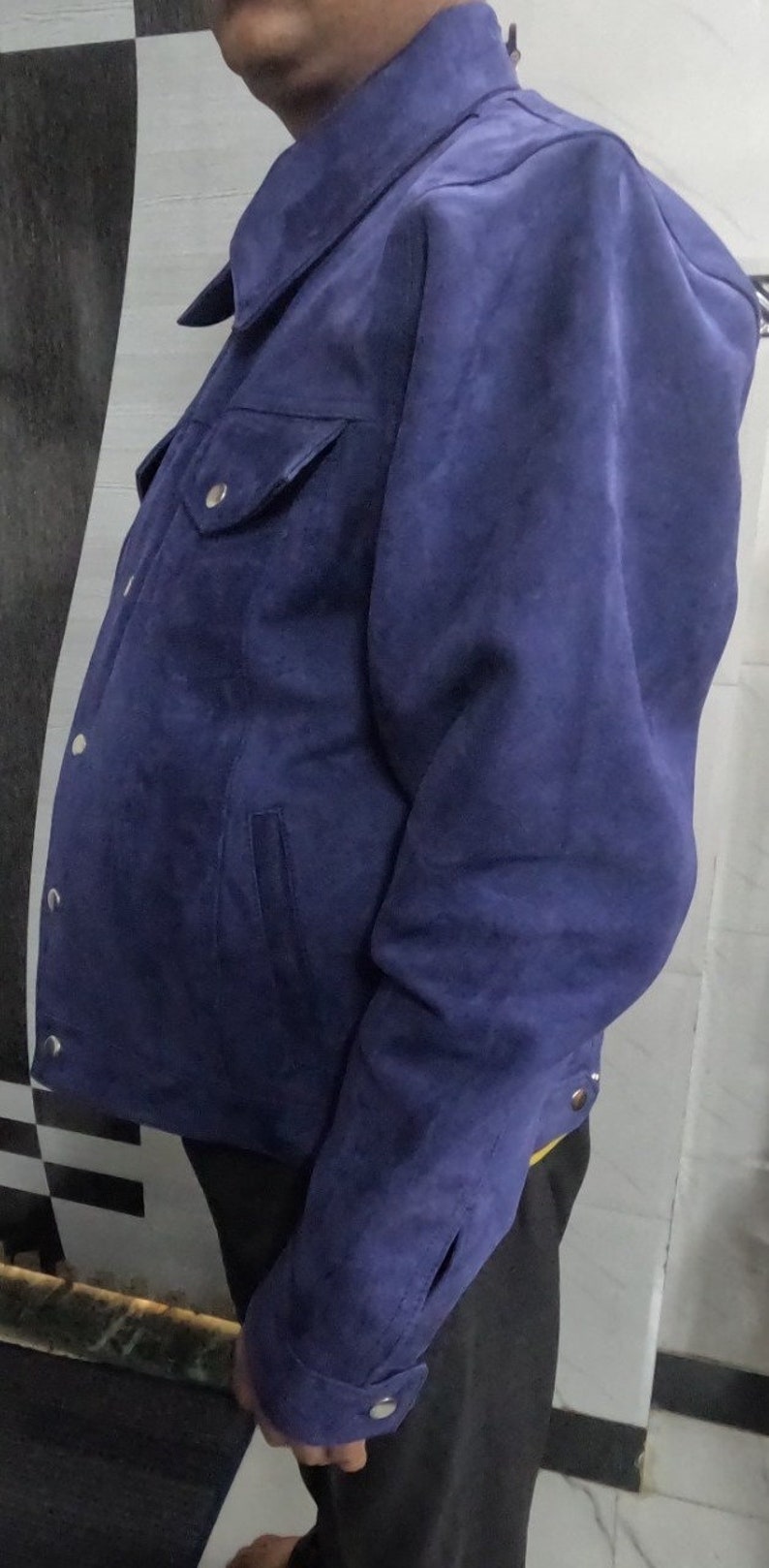 May include: A blue suede jacket with a button-up front and a single chest pocket.