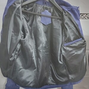 May include: A blue suede jacket with a black satin lining. The jacket has a zip closure and a pocket on the inside.