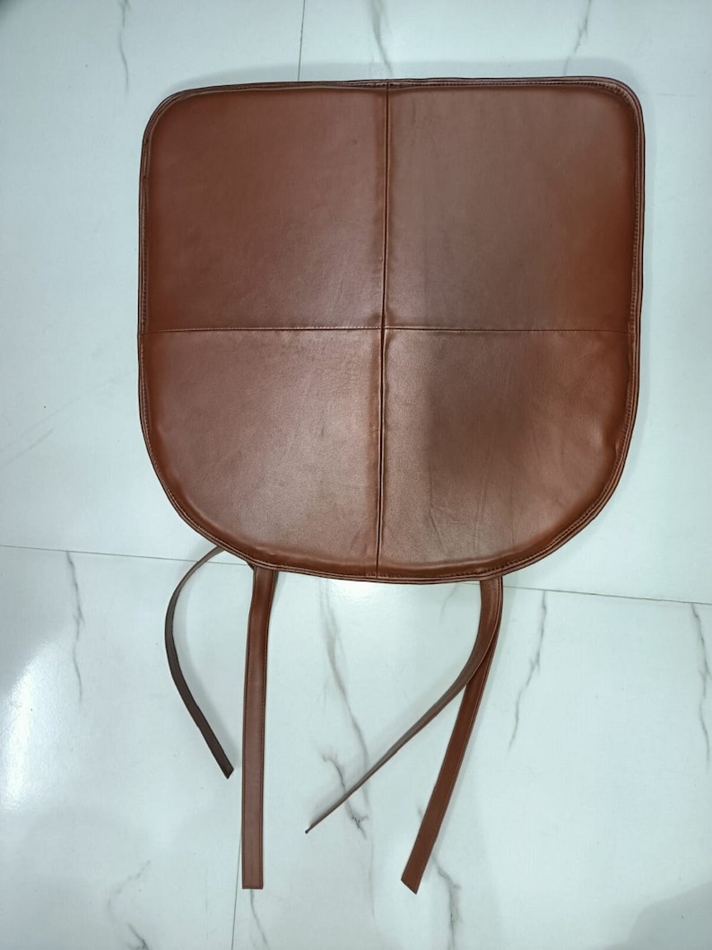 May include: Brown leather chair cushion with four stitched panels and two long ties.