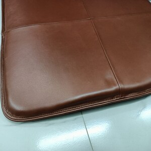May include: A brown leather seat cushion with a stitched edge.