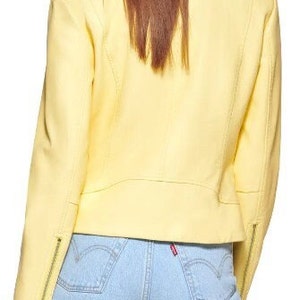 May include: A bright yellow leather jacket with a zipper closure. The jacket has a cropped fit and is worn over light blue jeans.