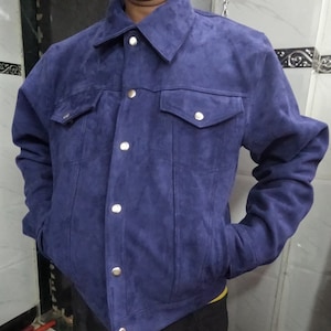 May include: A blue suede jacket with a button-up front and two flap pockets.