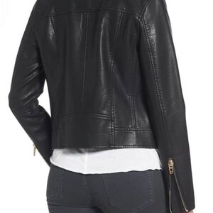 May include: Black faux leather moto jacket with zipper details. The jacket has a cropped fit and a stand-up collar.