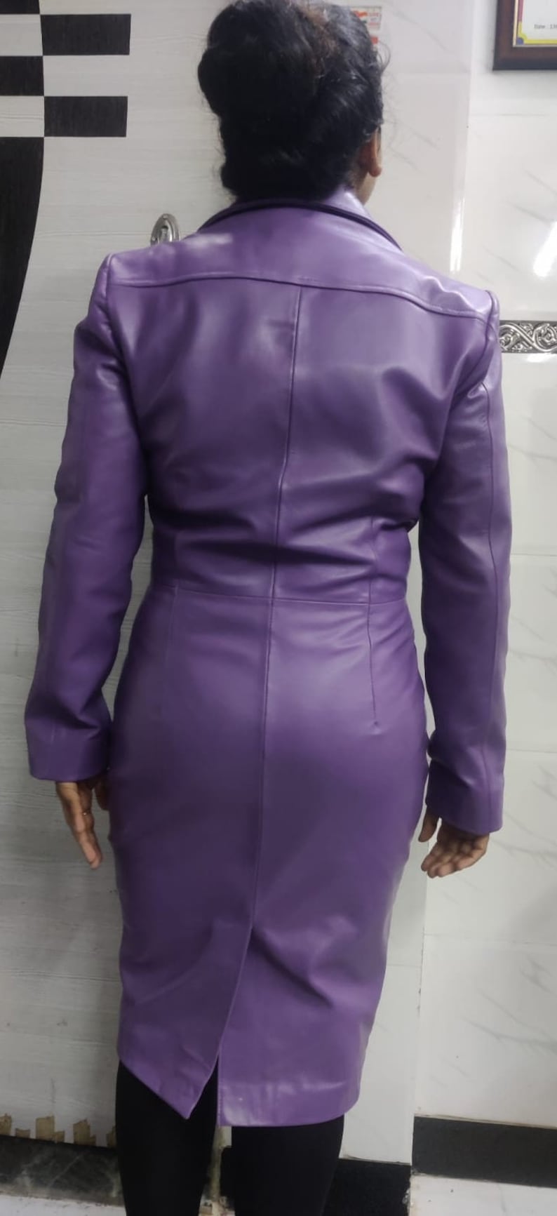 May include: A purple leather jacket with a long, fitted style. The jacket has a collar and long sleeves.