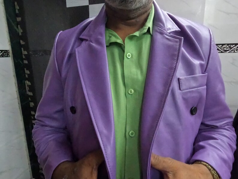 May include: A purple leather blazer with a double-breasted closure and a green button-down shirt underneath.