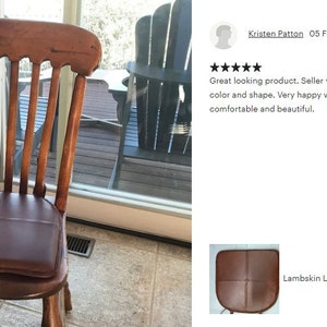 May include: A brown leather chair pad with a quilted design. The pad is placed on a wooden chair with a slatted back.
