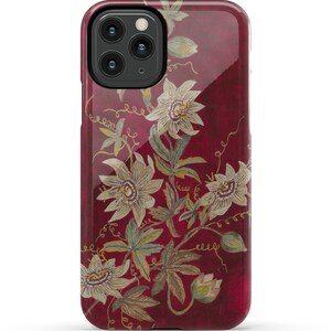 May include: A red phone case with a floral design featuring white flowers and green leaves. The flowers have a yellow center and are arranged in a pattern that resembles a vine.