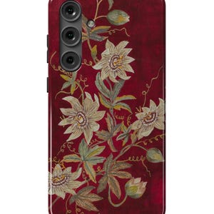 May include: A red phone case with a floral design featuring white flowers and gold accents.