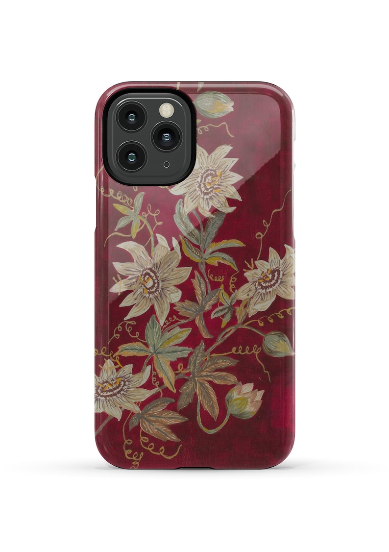 May include: A red phone case with a floral design featuring white flowers and green leaves. The case has a glossy finish.