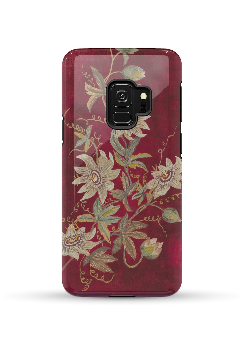 May include: A burgundy phone case with a floral design featuring white flowers and green leaves. The case has a cutout for the phone's camera.