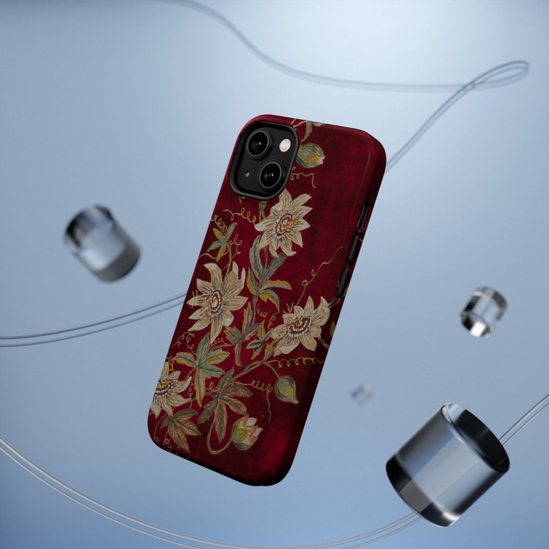 May include: A red phone case with a floral design featuring white flowers and green leaves. The case has a camera cutout and a textured surface.