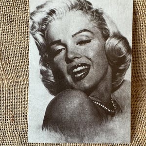Cartolina vintage con il ritratto di Marilyn Monroe, la Sofrançaise, con la mano sulla guancia.