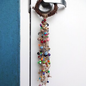 May include: A door handle with a wreath of twigs and a long strand of colourful beads hanging from it.