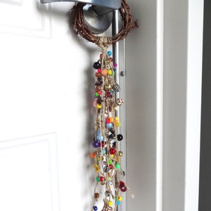 May include: A door handle with a twig wreath and a long strand of colourful beads hanging from it.