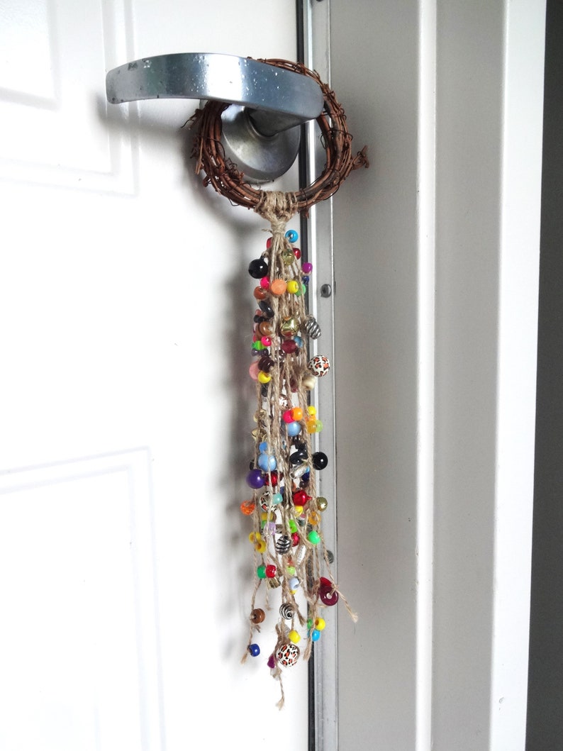 May include: A door handle with a twig wreath and a long strand of colourful beads hanging from it.