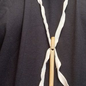Peut inclure: Un collier en cordon blanc avec un pendentif en sifflet en bois. Le sifflet est attaché au cordon avec un ruban blanc.