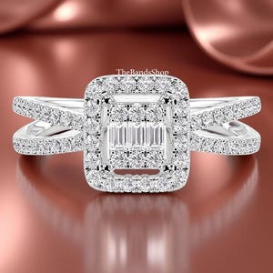 May include: A dazzling engagement ring with a square halo design. The center features a cluster of baguette-cut diamonds, surrounded by a square halo of smaller, round-cut diamonds. The split shank band is also adorned with sparkling diamonds, creating a brilliant display.