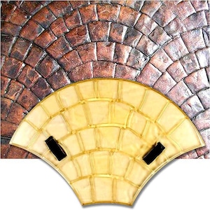 May include: A fan-shaped, light yellow object with a grid pattern and two black rectangular accents. The object is set against a textured, brown, brick-like background, creating a contrast in color and texture.