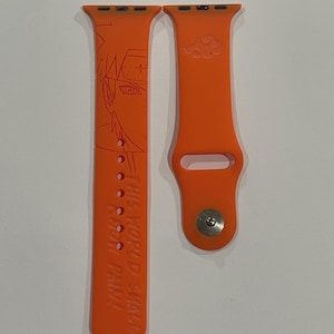 Può includere: Cinturino per Apple Watch arancione brillante con un design dettagliato di personaggi anime e la scritta "THIS WORLD SHALL KNOW PAIN". Il cinturino include anche un simbolo di nuvola.