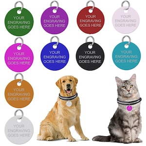 May include: Ten round, blank pet ID tags in various colours, including green, purple, red, pink, blue, black, brown, and silver. The text on each tag reads "Your Engraving Goes Here". A golden retriever dog and a grey cat are wearing collars with tags.