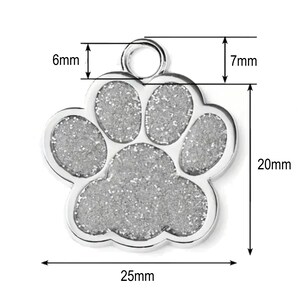May include: Silver paw print dog tag with a sparkly finish. The tag measures 25mm wide, 20mm tall, and has a 6mm diameter ring.