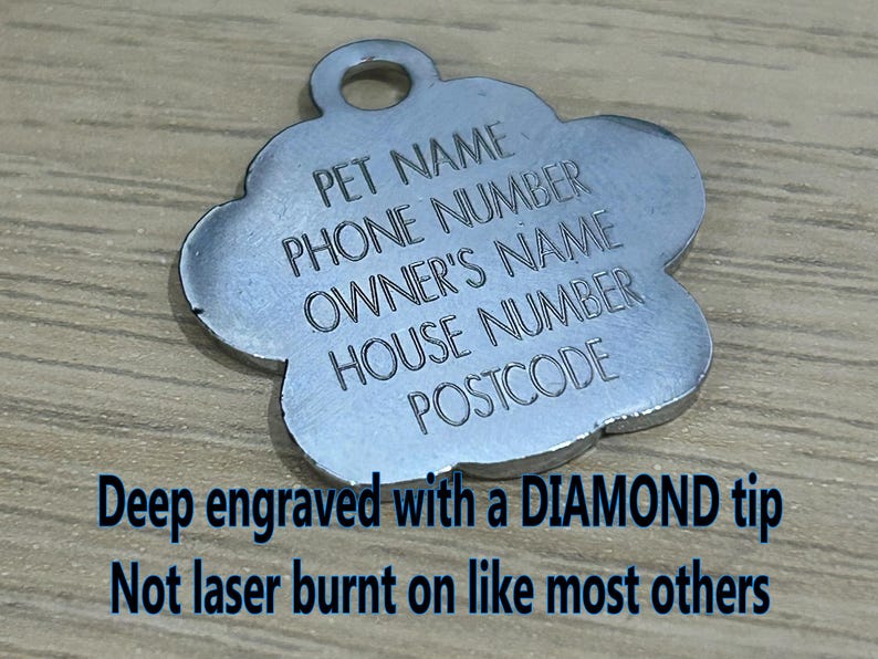 May include: Silver paw-shaped pet ID tag with engraved text: "PET NAME", "PHONE NUMBER", "OWNER'S NAME", "HOUSE NUMBER", "POSTCODE". The tag is deep engraved with a diamond tip, not laser burnt.