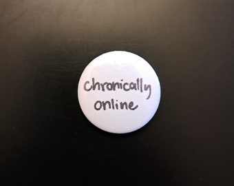 May include: White button with the text "chronically online" written in black ink.