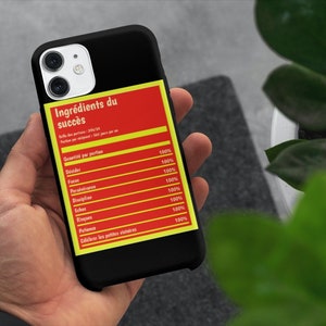 May include: A black phone case with a red and yellow label that reads "Ingrédients du succès" and lists ingredients for success, including focus, discipline, and risk.