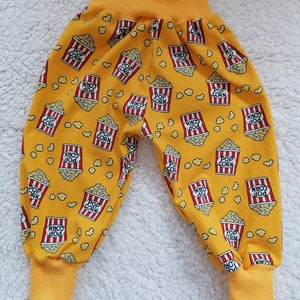 Könnte beinhalten: Gelbe Kinderhose mit Popcorn-Druck. Die Hose hat einen elastischen Bund und Bündchen an den Beinen.