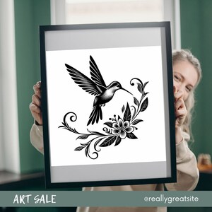 K&ouml;nnte beinhalten: Schwarzwei&szlig;-Illustration eines Kolibris mit seinem Schnabel in einer Bl&uuml;te. Der Kolibri ist von stilisierten floralen Designs umgeben.