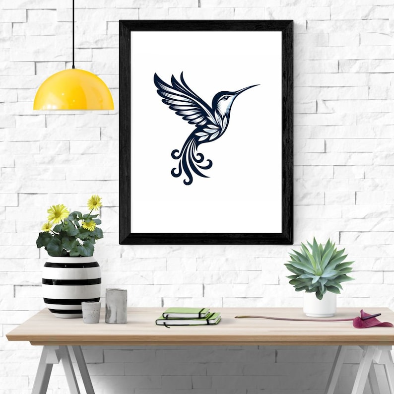 May include: A black framed print of a stylized hummingbird with a blue and white design. The hummingbird is flying with its wings spread out and its tail feathers are curled. The print is hanging on a white brick wall.