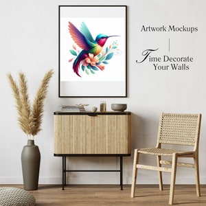 May include: A framed artwork featuring a vibrant hummingbird with colorful wings and a long beak, surrounded by flowers and leaves. The artwork is displayed above a wooden cabinet with a black frame, next to a woven chair.