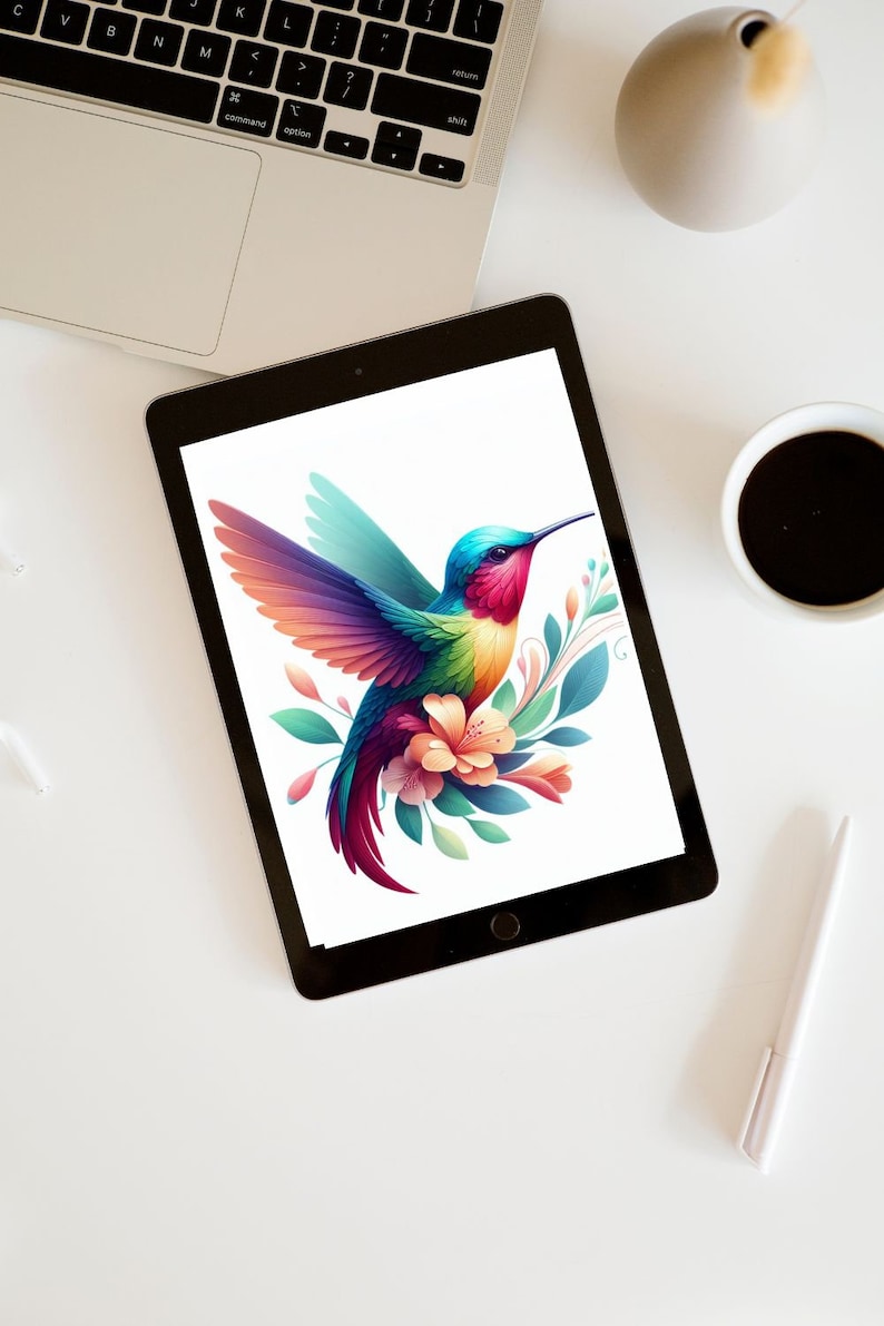 May include: A digital tablet displays a vibrant illustration of a hummingbird with colorful wings, a long beak, and a floral arrangement. The bird's feathers transition from blue to red, with green and orange accents. The tablet is on a white surface.