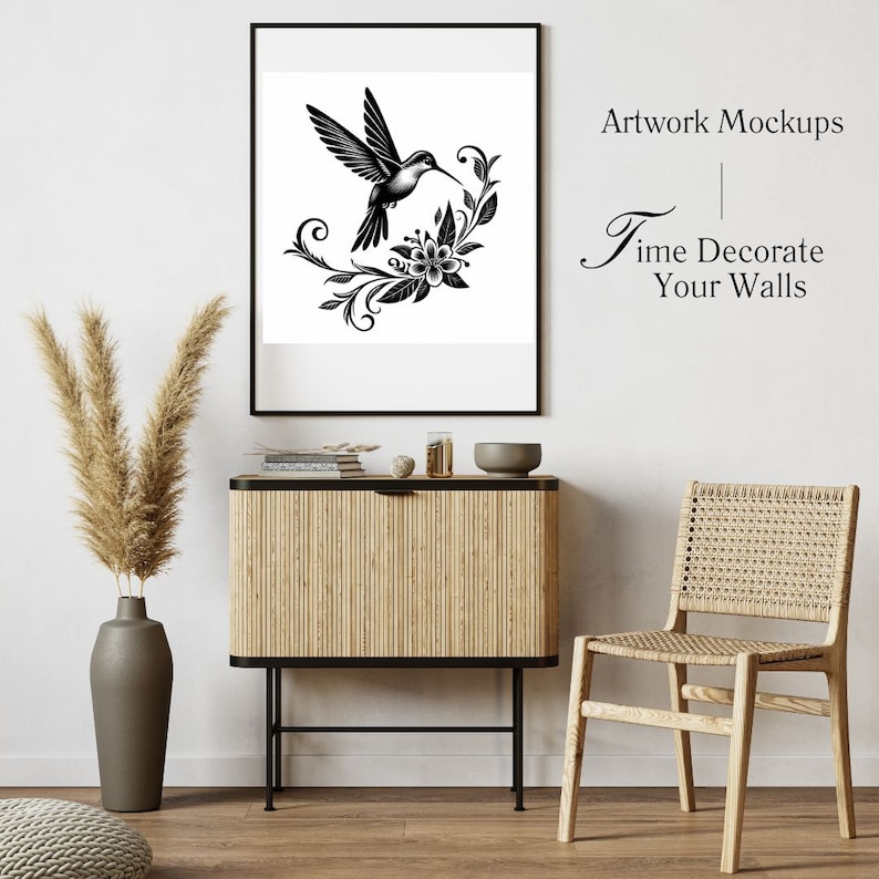 K&ouml;nnte beinhalten: Schwarzwei&szlig;-Illustration eines Kolibris mit Blumen in einem schwarzen Rahmen, der an einer wei&szlig;en Wand &uuml;ber einem Holzschr&auml;nkchen mit einem Korbstuhl rechts h&auml;ngt. Der Text "Artwork Mockups" und "Time Decorate Your Walls" ist in der oberen rechten Ecke des Bildes sichtbar.