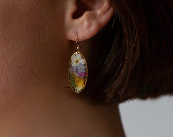 Boucles d'oreilles ovales en résine époxy, fabriquées à partir de fleurs sauvages colorées pressées. Ces boucles d'oreilles aux couleurs éclatantes sont réalisées avec de véritables fleurs séchées.