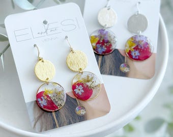Boucles d'oreilles en résine époxy aux fleurs sauvages colorées, ornées de petites fleurs variées et de pendentifs.
